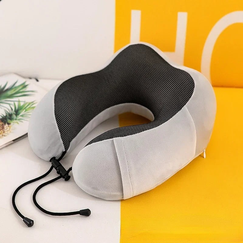 Gray and black neck pillow on a yellow surface with a blurred background
